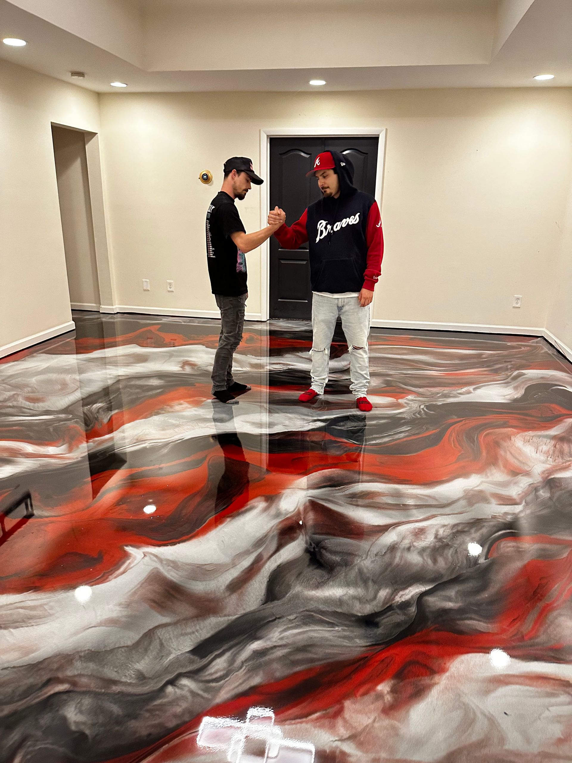 Two people standing in a room with a large red, white, and black abstract floor mural