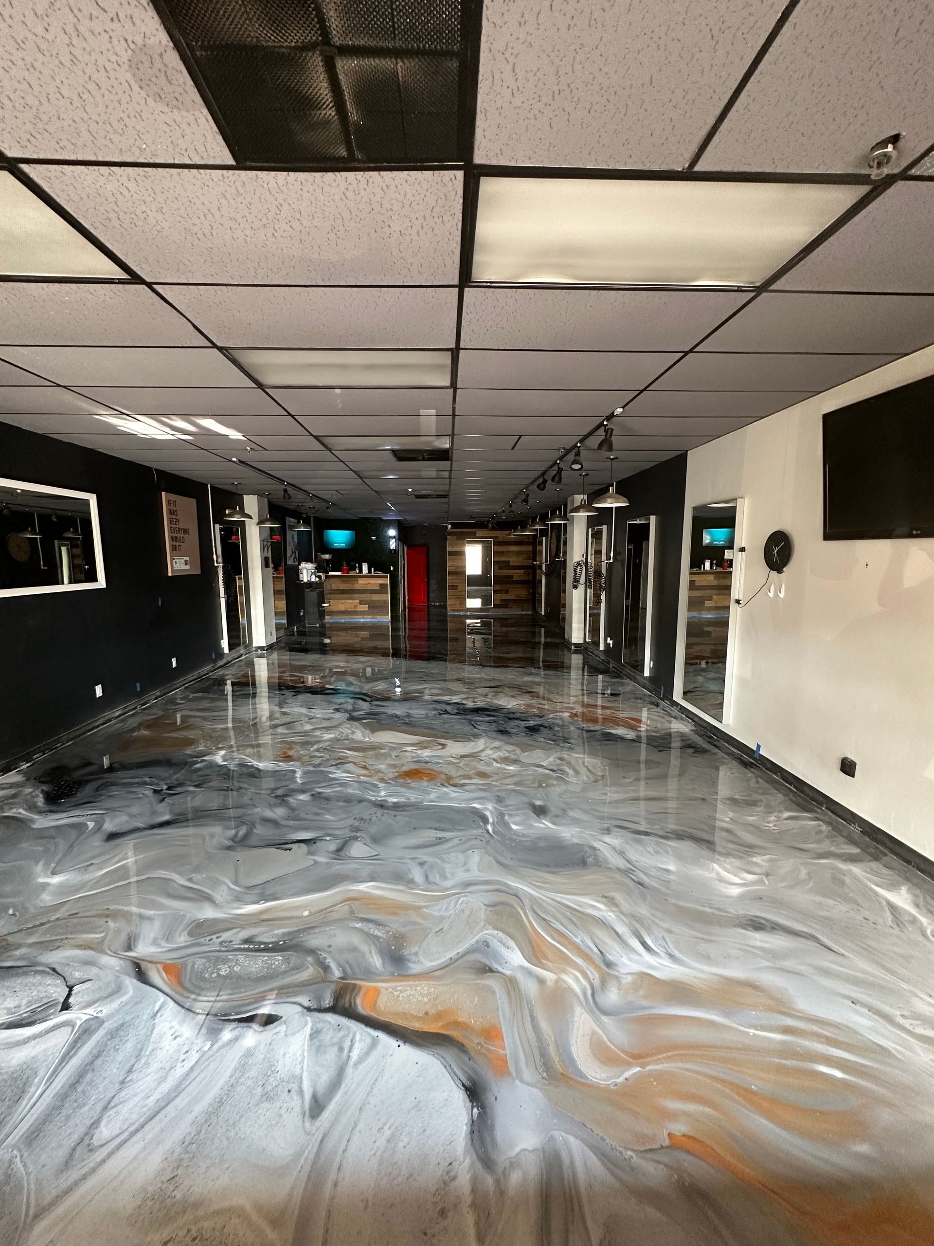 Flood-damaged hallway with water-covered floor, stained ceiling tiles, and debris in a dark interior corridor