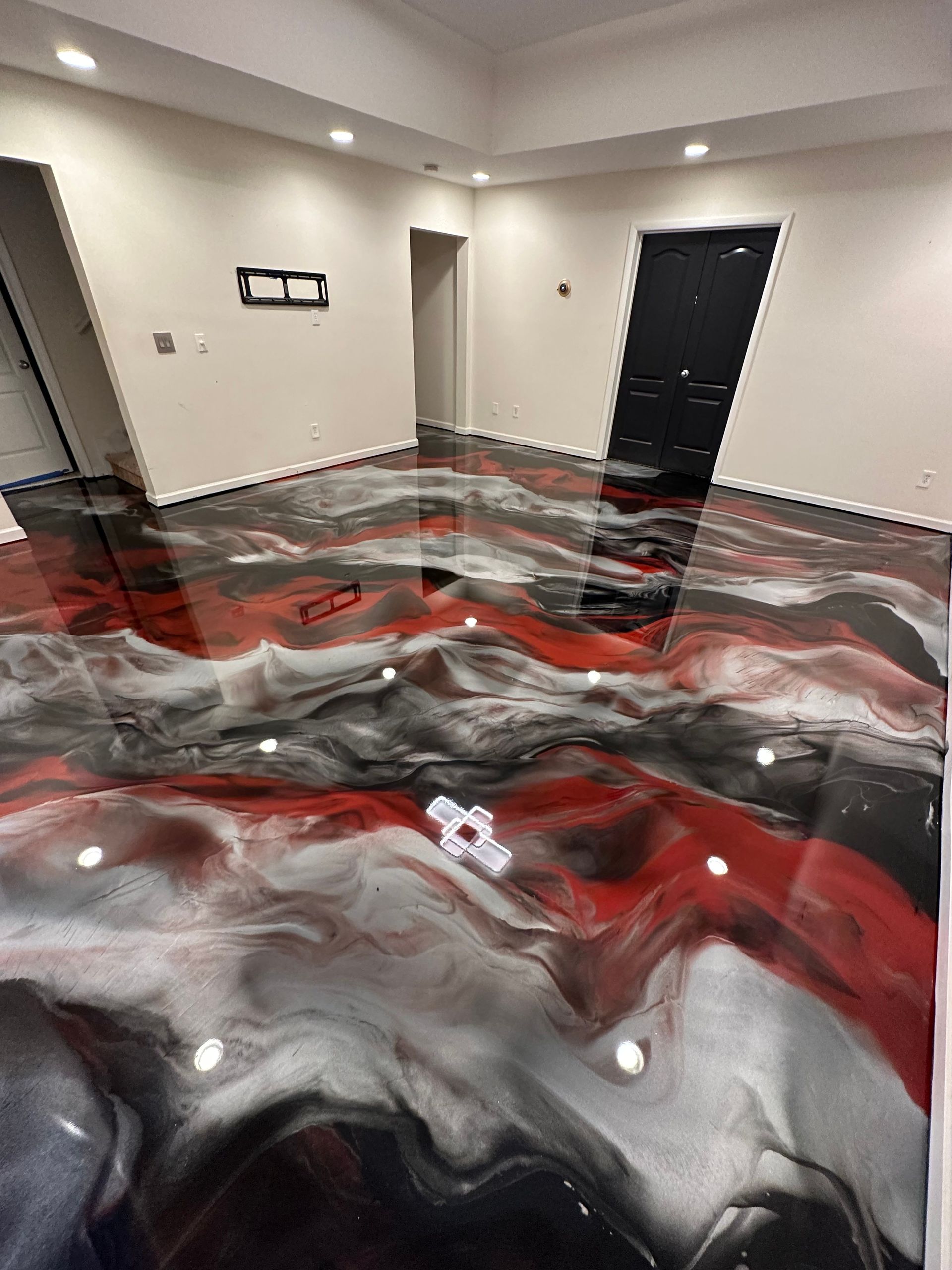 Empty room with glossy red, black, and white marbled floor and beige walls