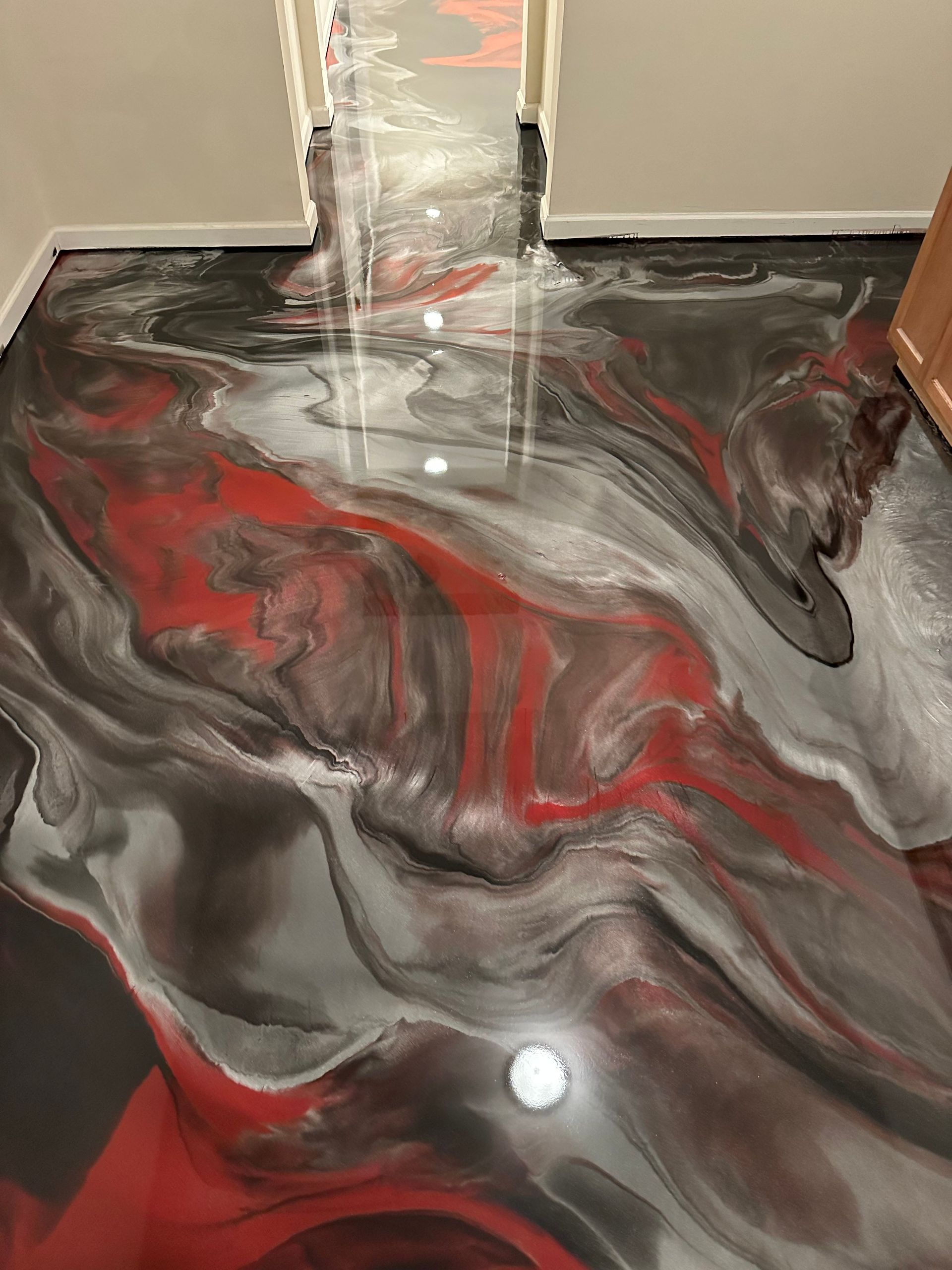 Glossy black, red, and gray marbled floor in a hallway with a doorway at the end