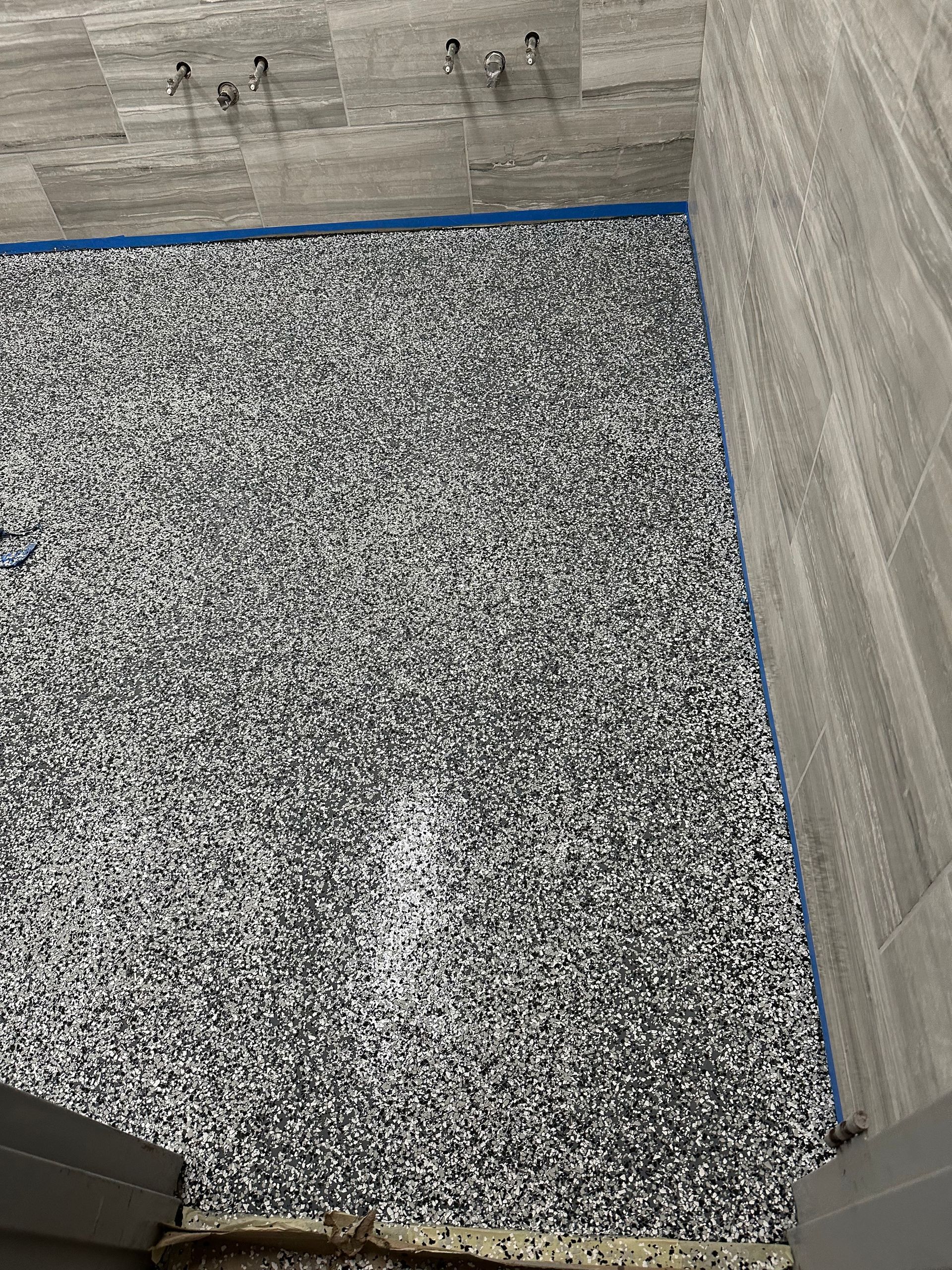 Small gravel-covered area bordered by gray walls and a blue edging strip