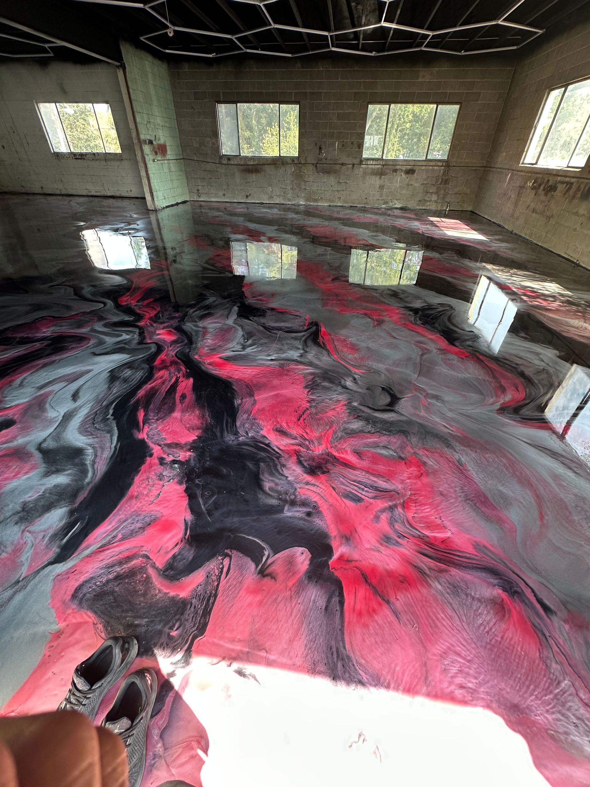 Large indoor room with a glossy black floor swirled with bright pink and gray marbling.