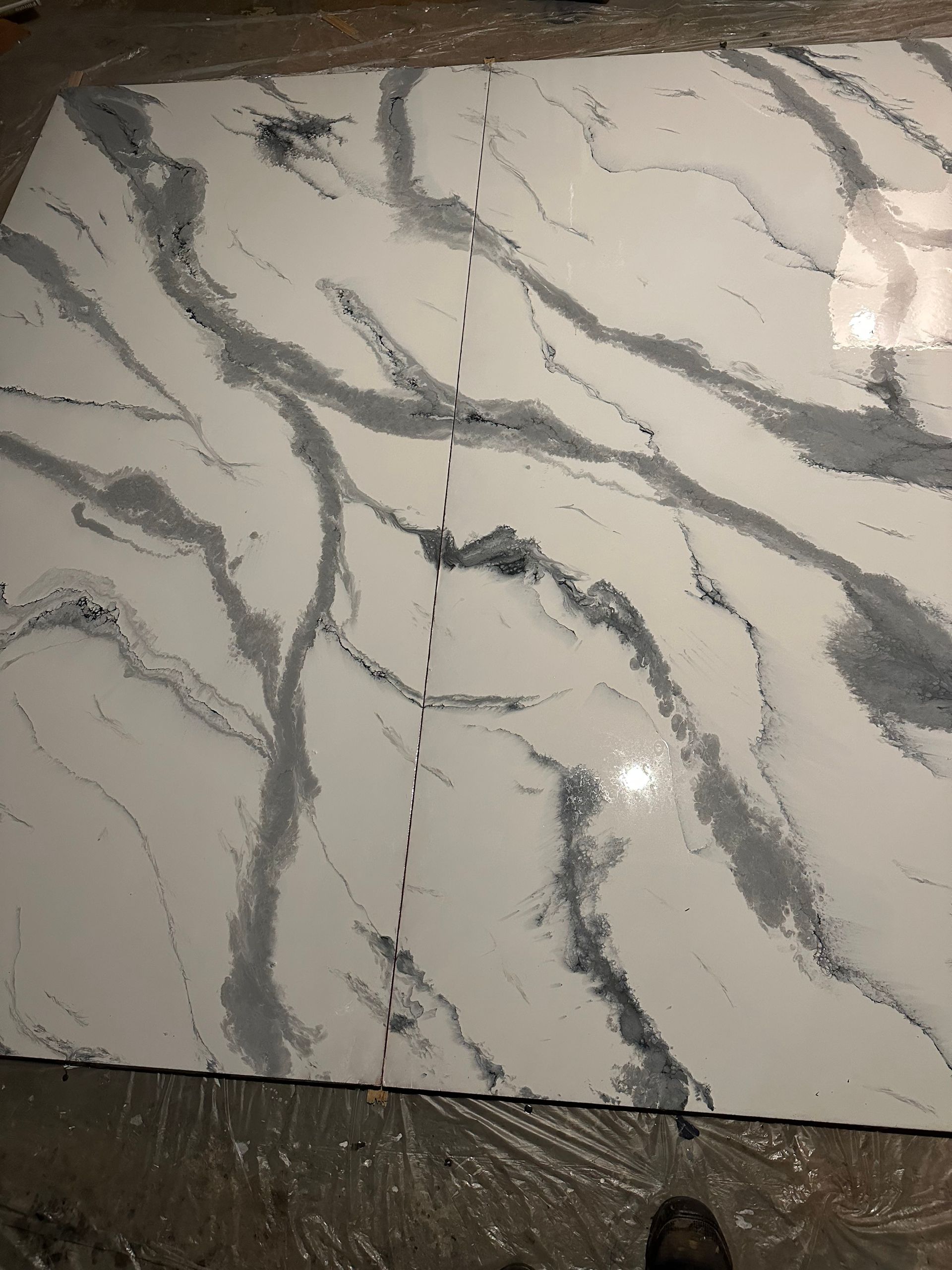 White marble-look tile with gray veining and a vertical crack or seam down the center.
