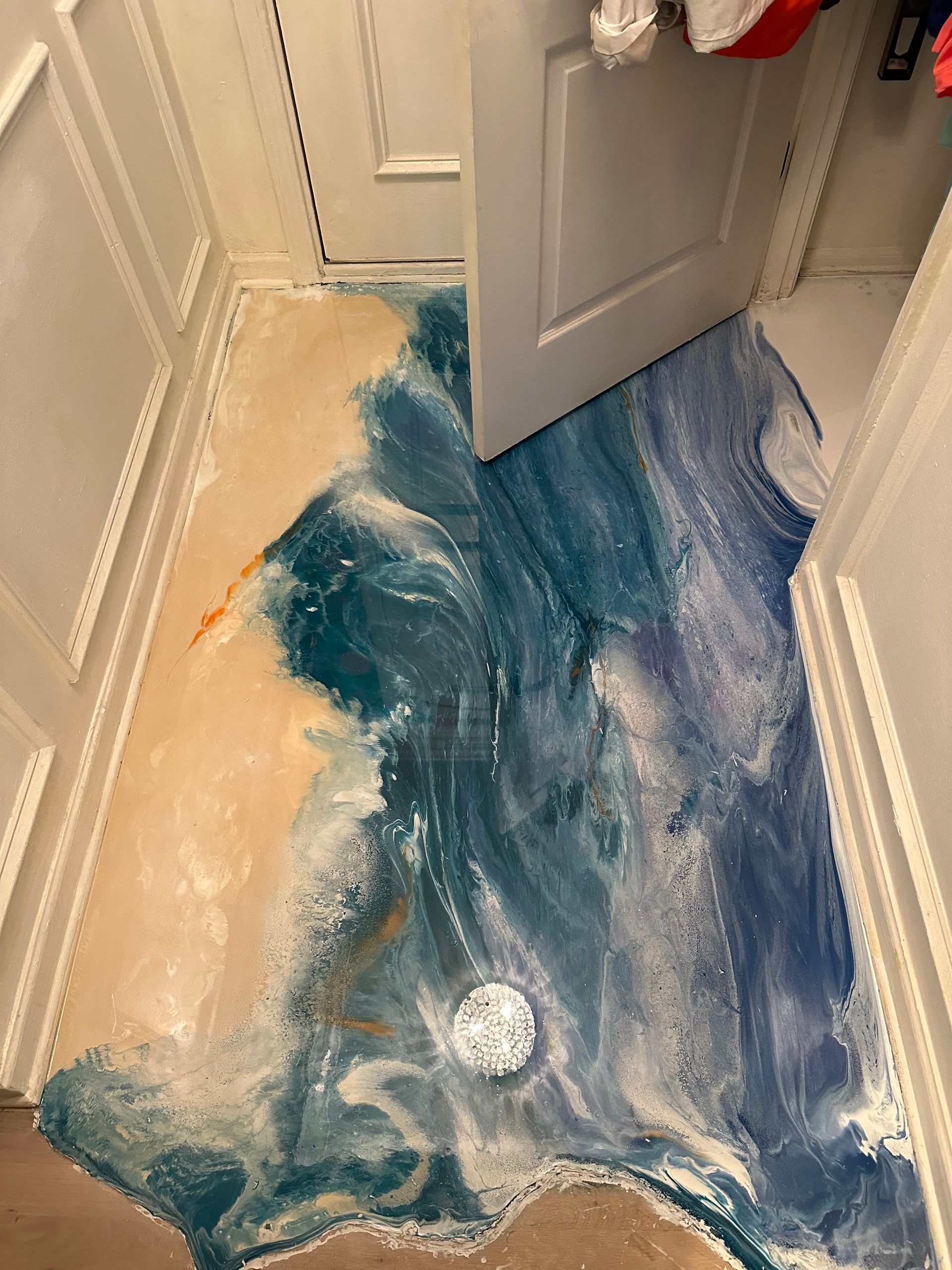 Blue liquid spilled across a hallway floor near an open door