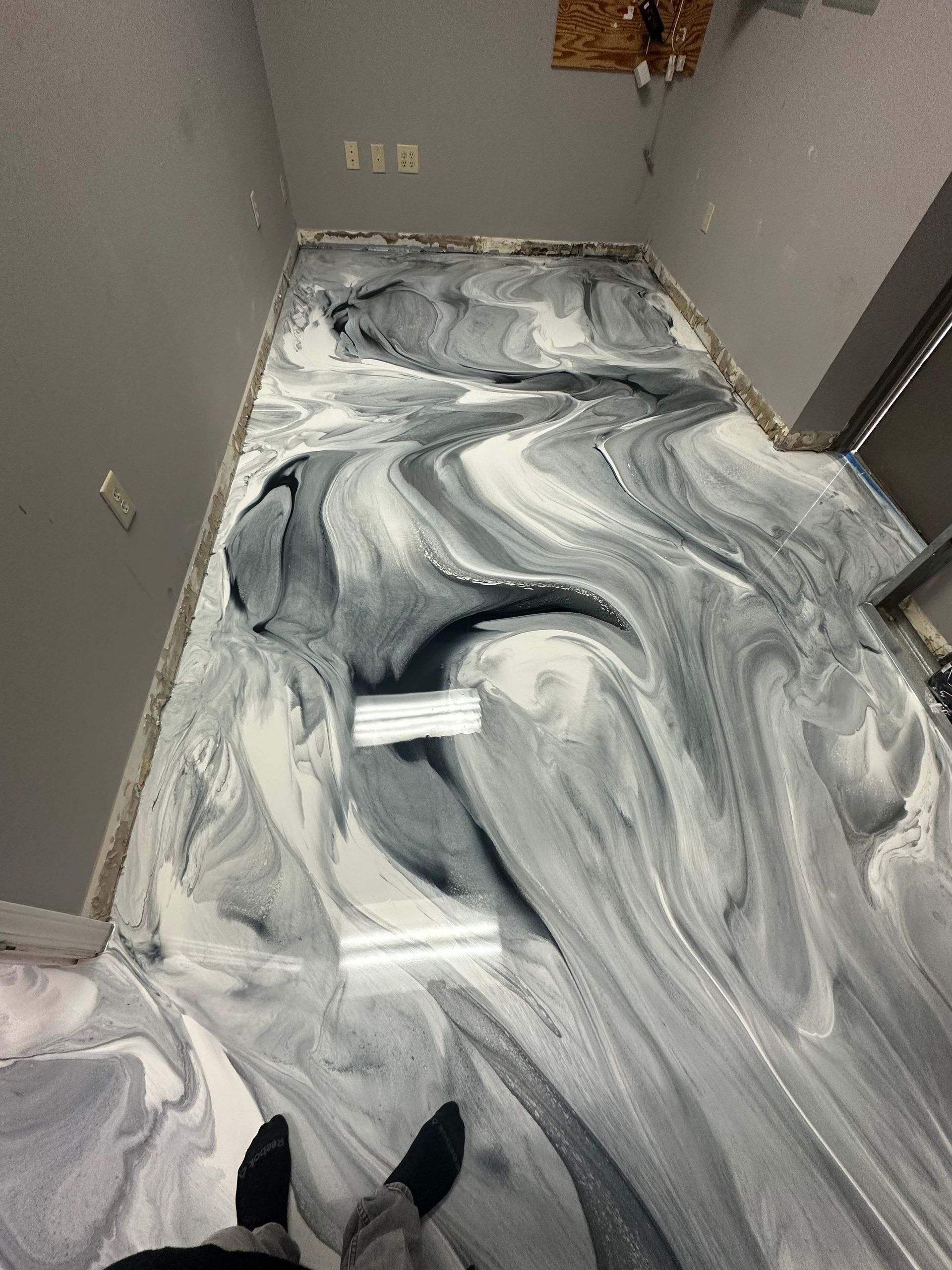 Hallway floor covered in white-gray liquid, with a pair of shoes visible at the bottom edge.
