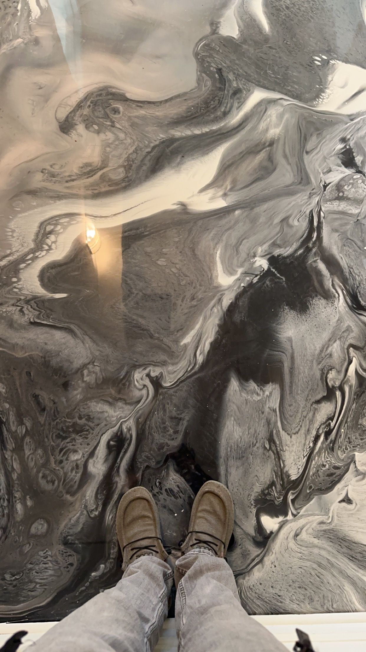 Boots on pale sand beside dark, swirling wet patterns at the beach