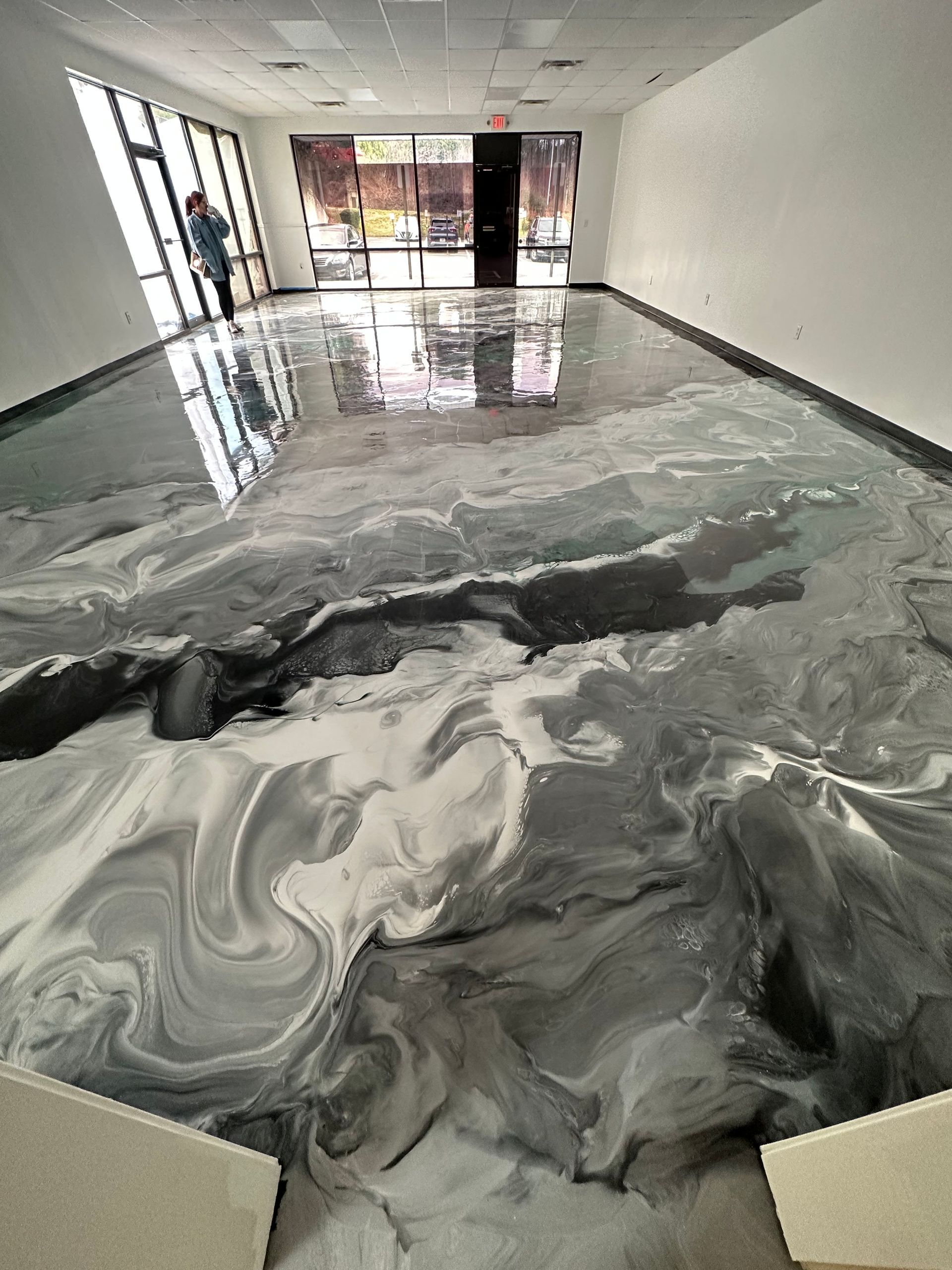 Empty hallway with a glossy black-and-gray floor marbled with swirling liquid or epoxy.