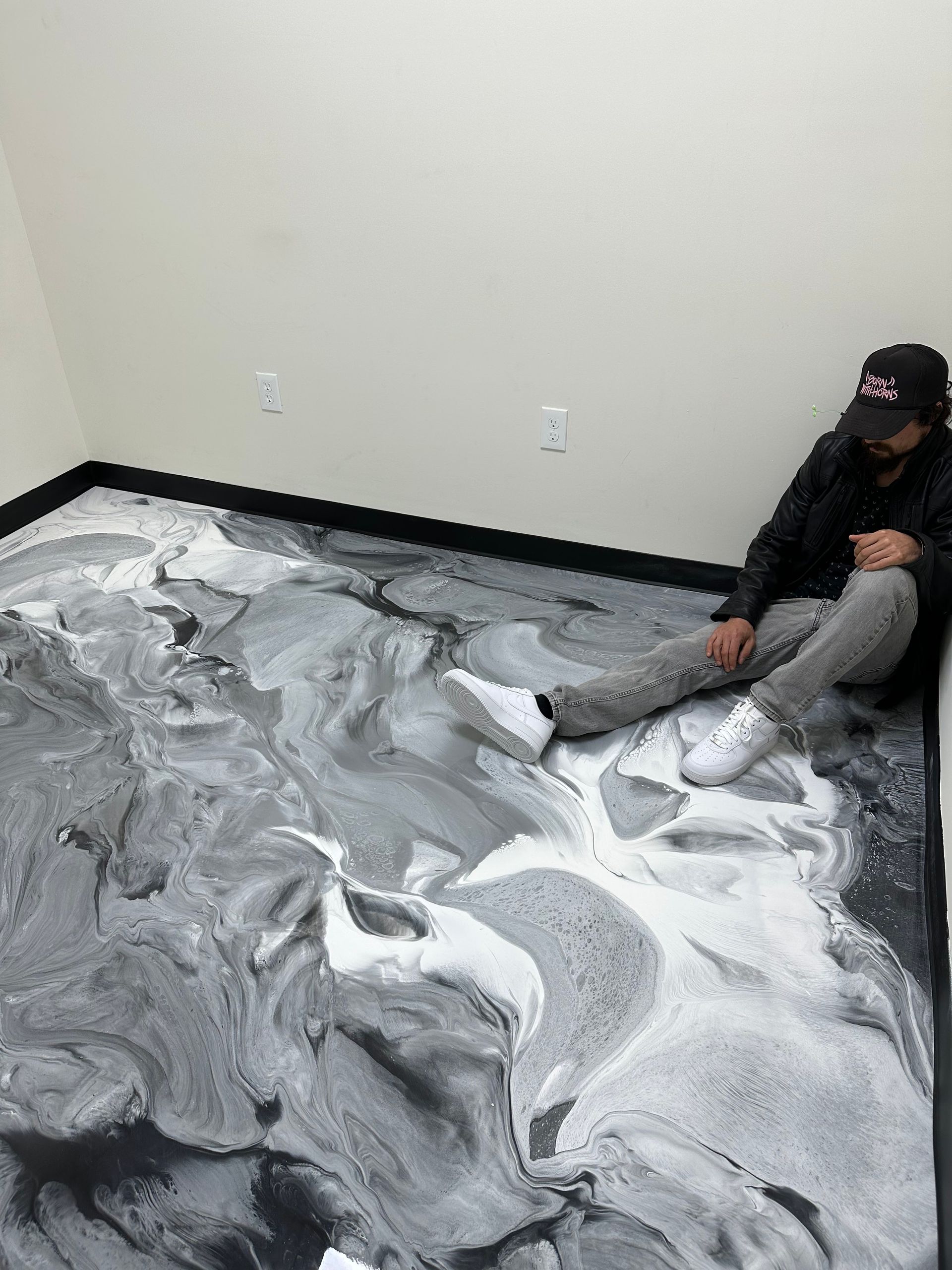 Person sitting on a floor covered in gray and white powder in an empty room