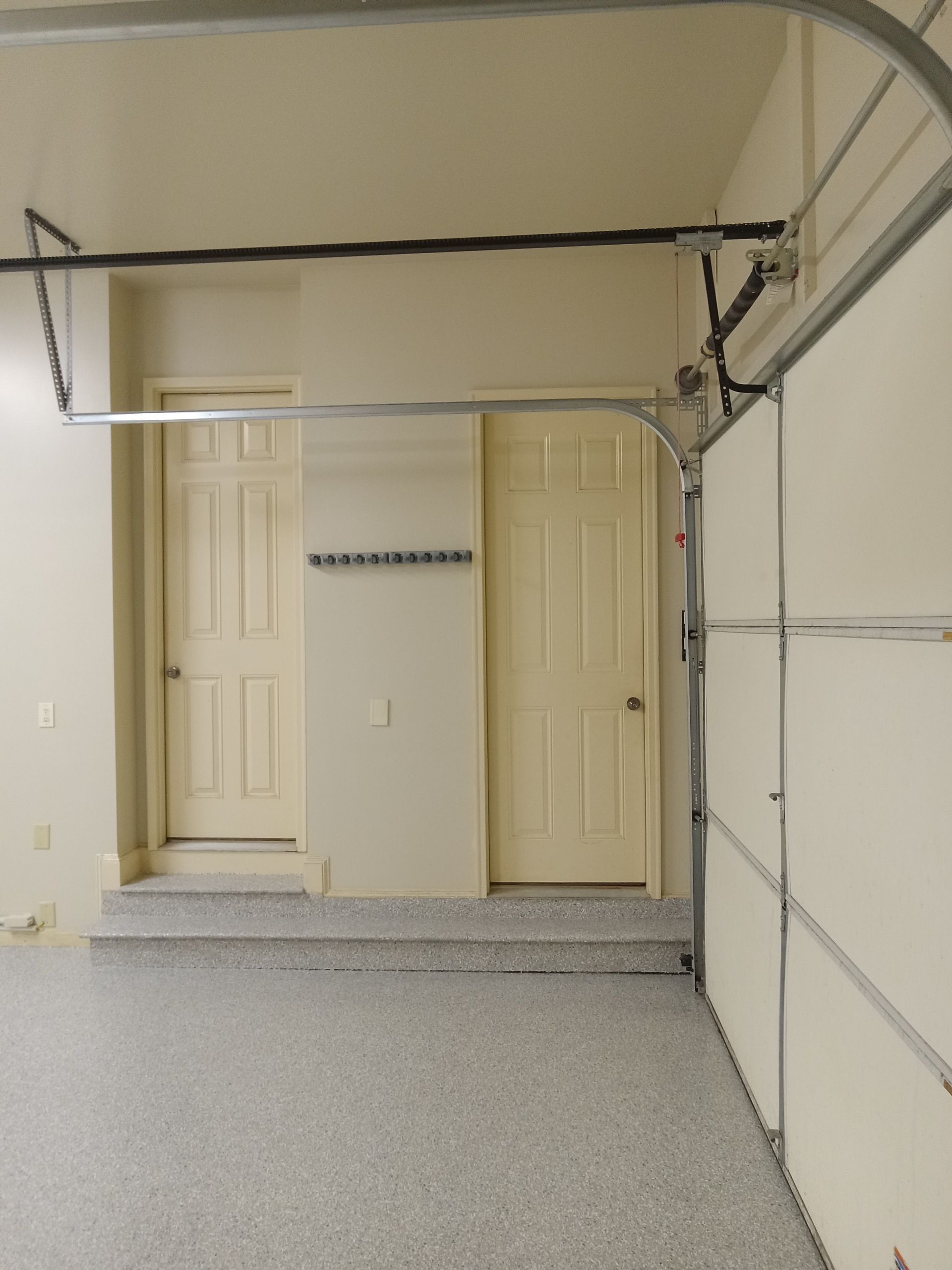 Empty garage interior with beige doors and closed overhead opener rails.
