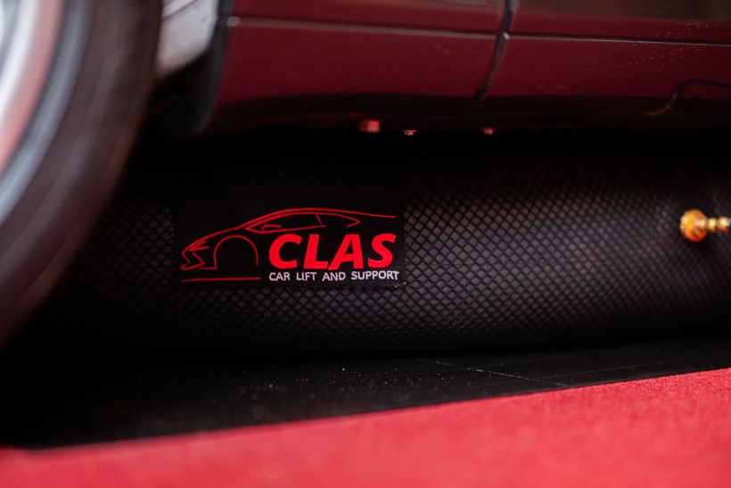Rødt CLAS-logo på et sort tekstureret panel ved siden af ​​et rødt bilinteriør
