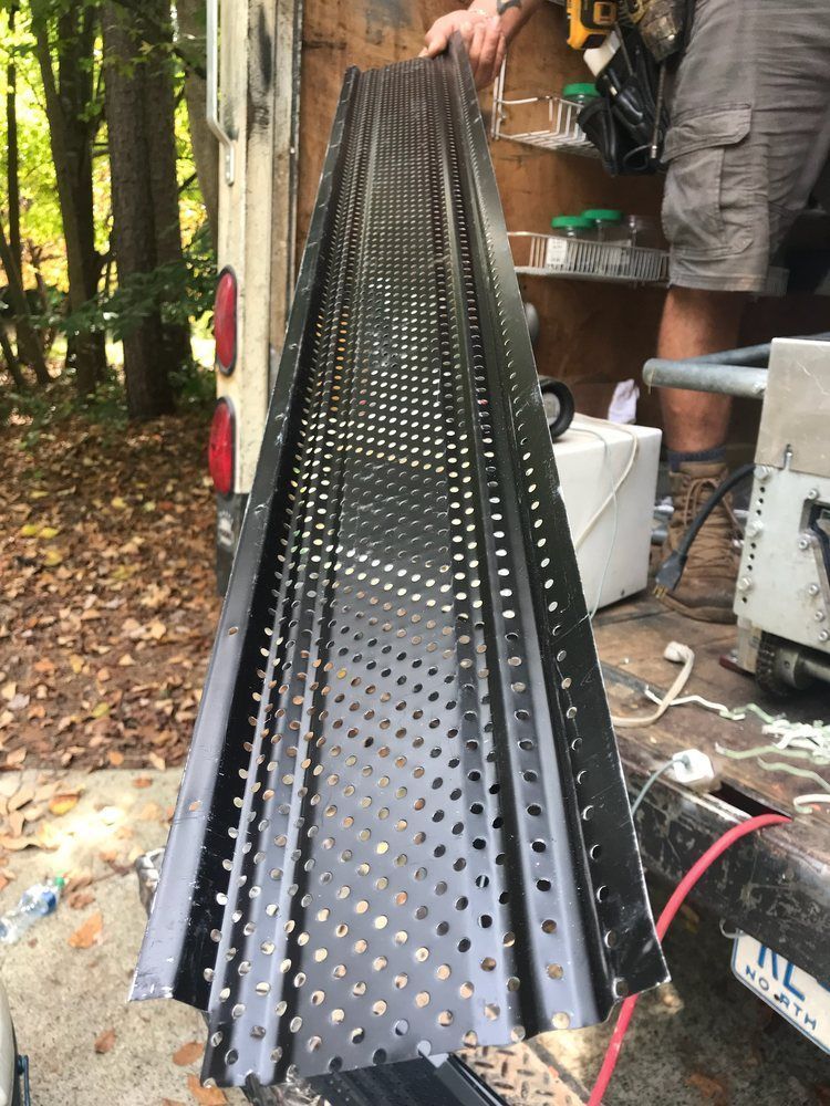 A man is holding a piece of metal that looks like a roller coaster.