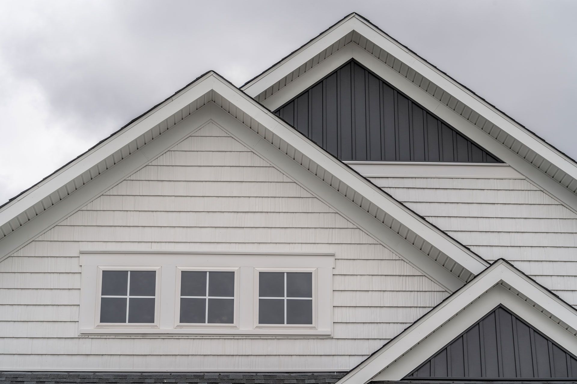 A white house with a black roof and a gray sky in the background.
