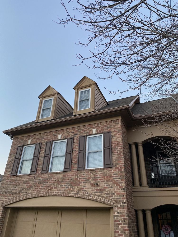 A large brick house with a garage and shutters on the windows.