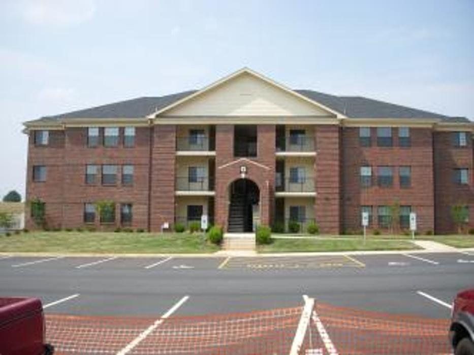 A large brick apartment building with a parking lot in front of it