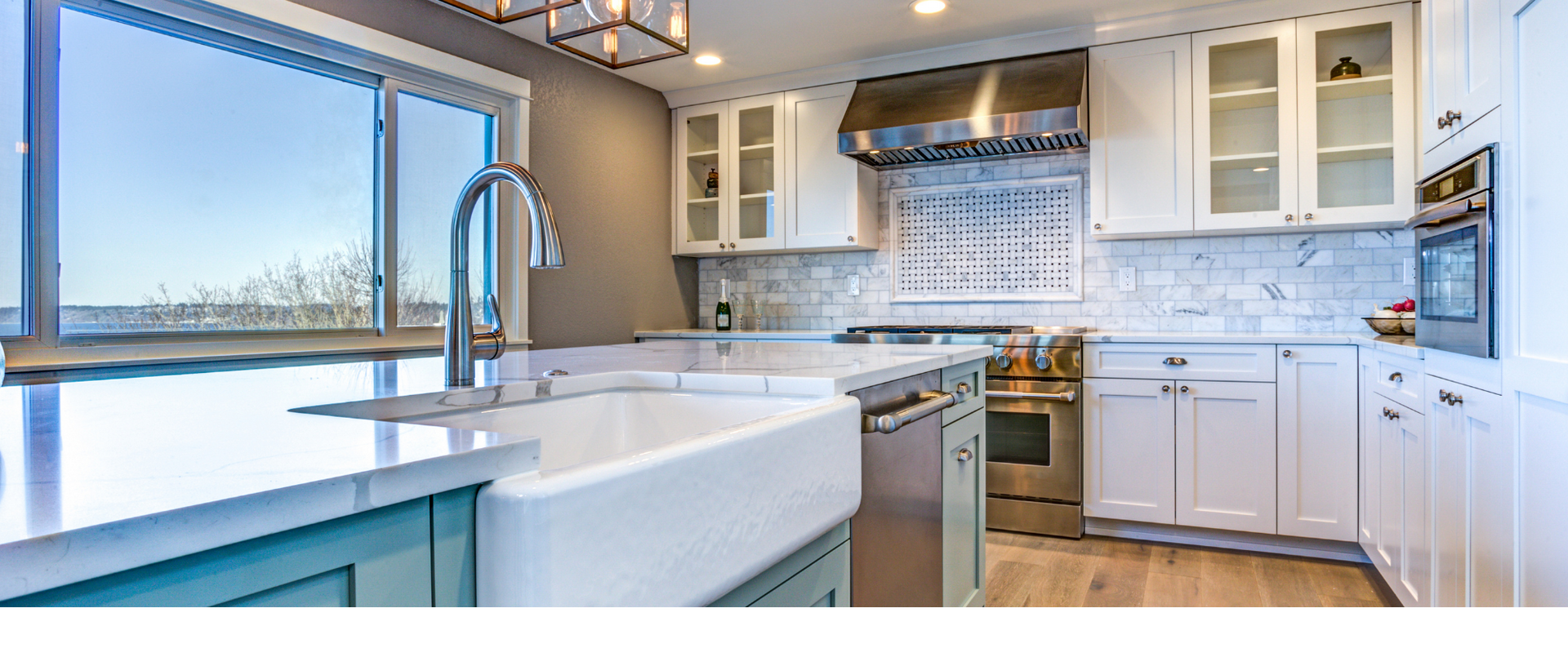 Bright modern kitchen with white cabinets, blue island, large window, and stainless-steel appliances