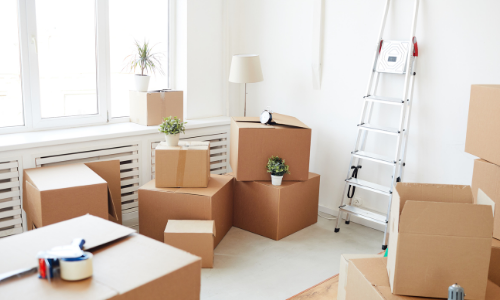Moving boxes and a ladder in a bright room during packing or renovation