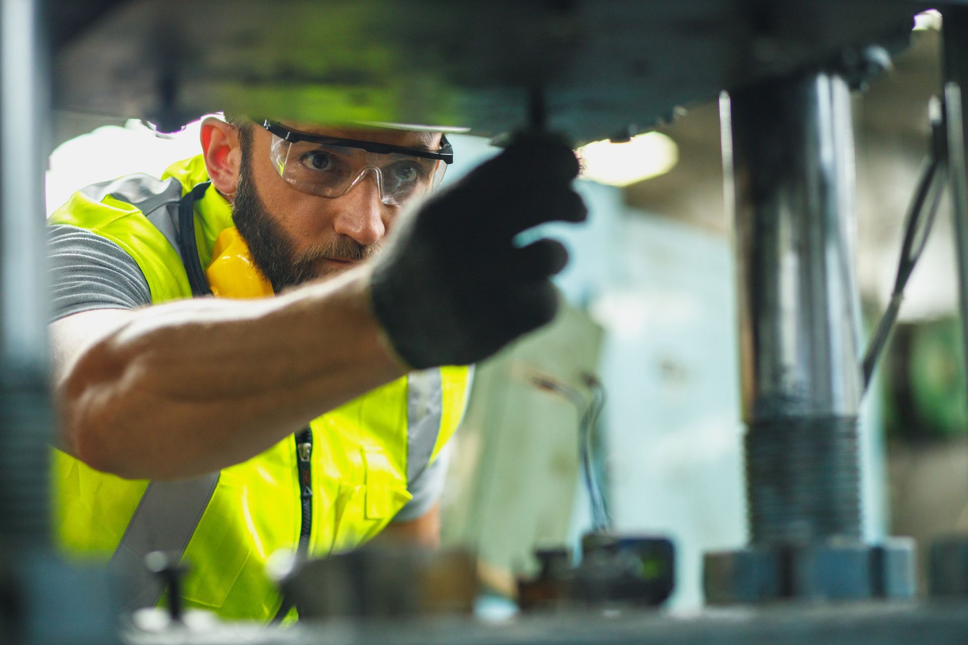 Un homme en tenue de sécurité inspecte des machines dans une usine.