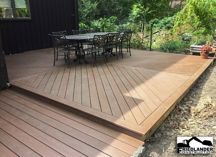 Wooden deck with outdoor dining table and chairs beside a garden and covered patio