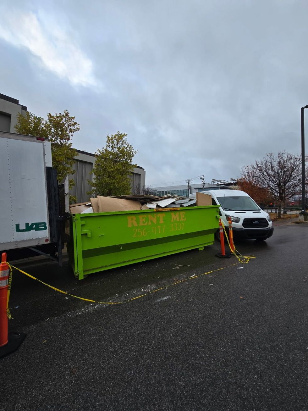 Large black dumpster on a suburban driveway in front of beige houses