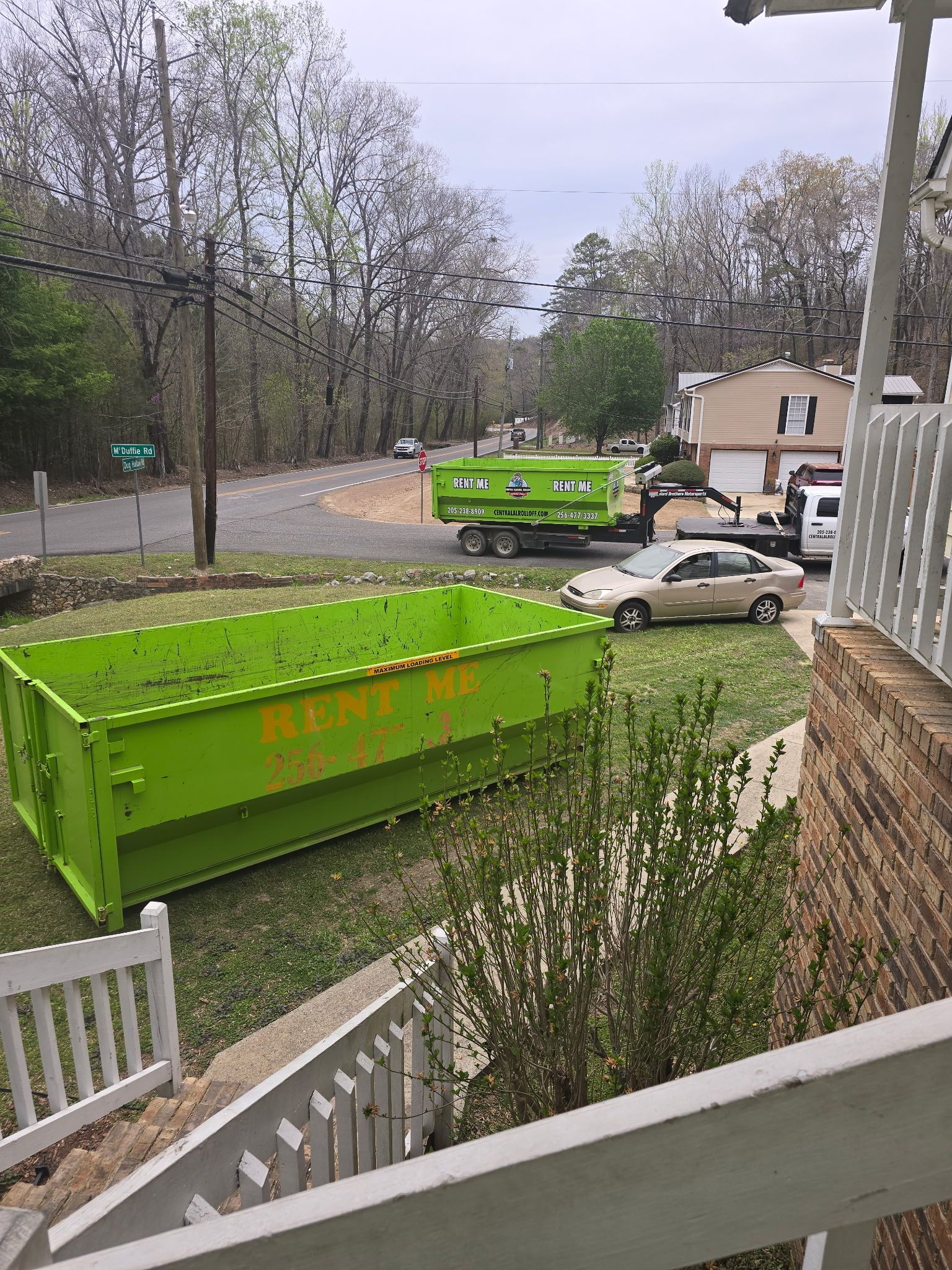 Garbage truck unloading bulky trash as two workers sort items in a suburban driveway