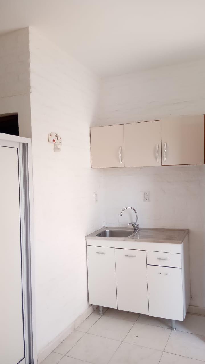 Una cocina pequeña con fregadero, armarios y un refrigerador blanco.