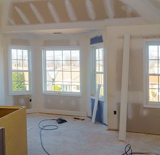 a room that is being remodeled with a lot of windows and drywall .