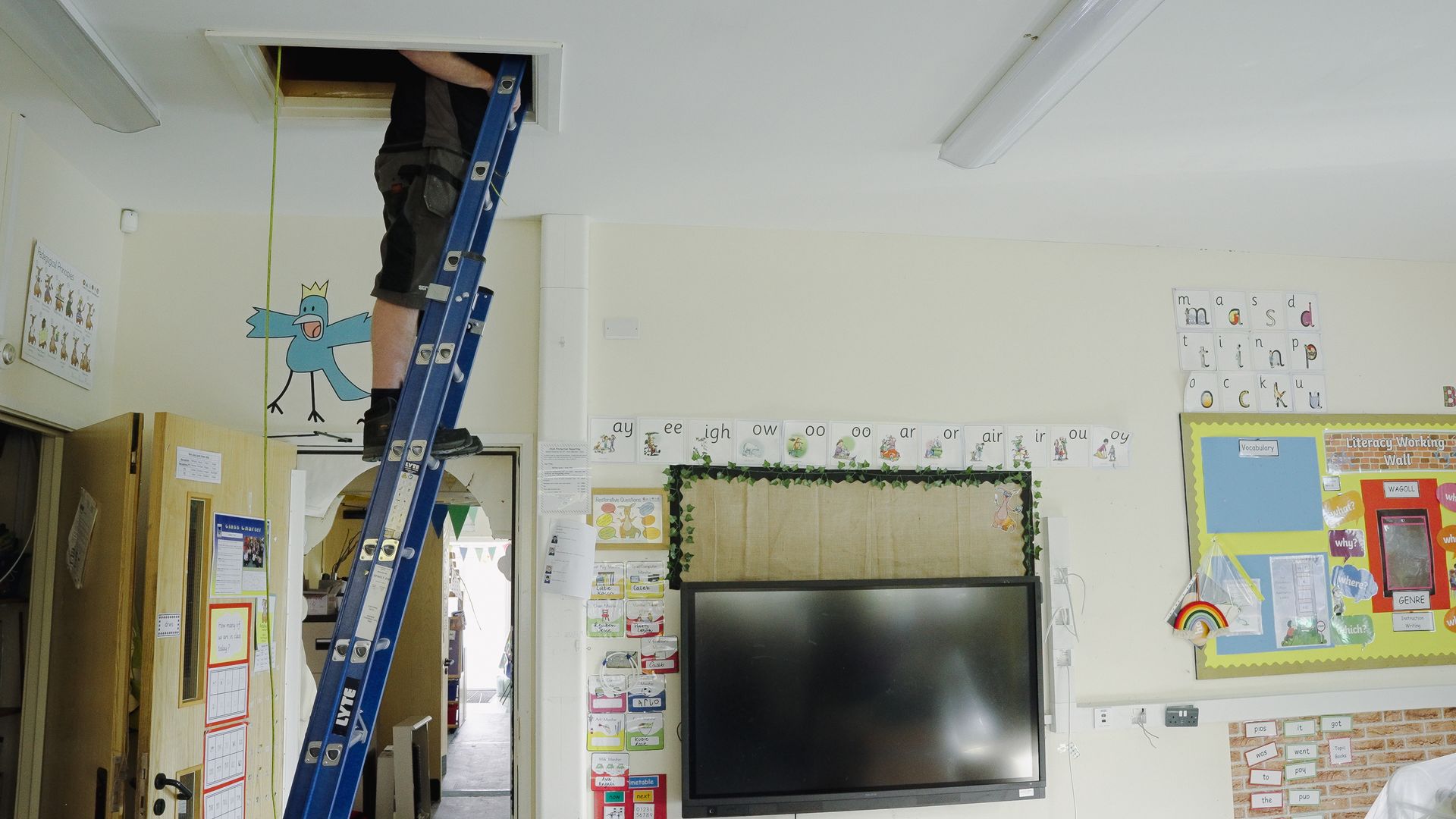 Electrician on an fibreglass extension ladder accessing a loft space