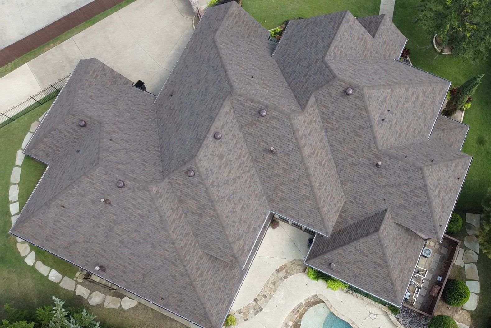 Aerial view of a large gray-shingled house with multiple gables and a backyard pool.