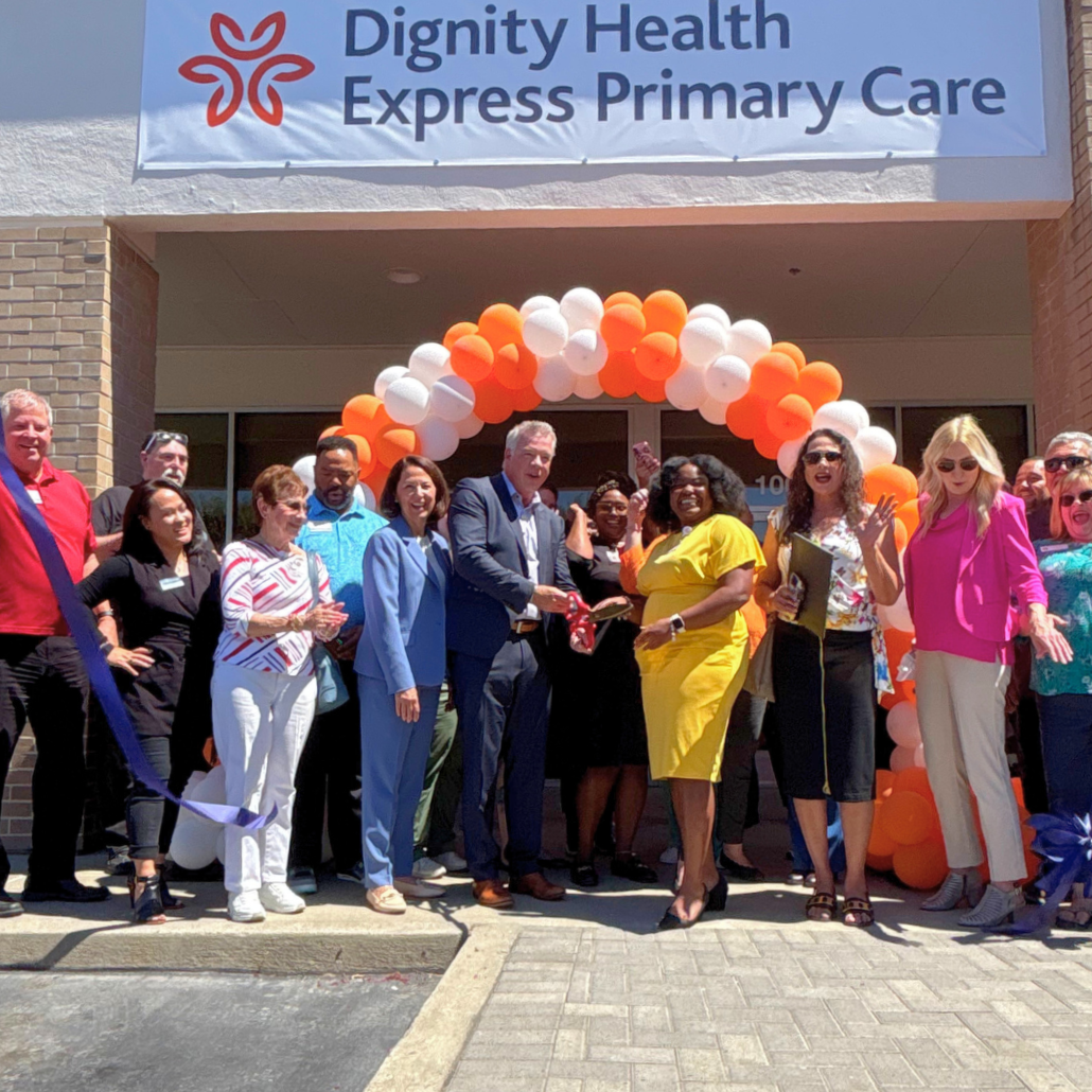 People cutting a ribbon at a Dignity Health Express Primary Care grand opening with balloon arch.