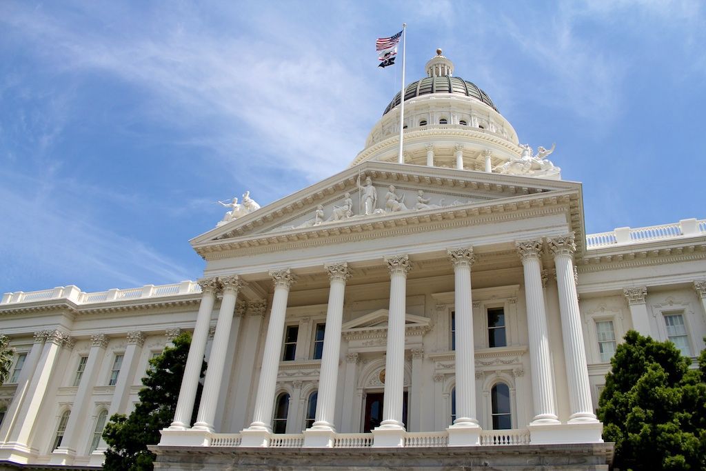 California State Capitol building with white columns and dome, under a blue sky.