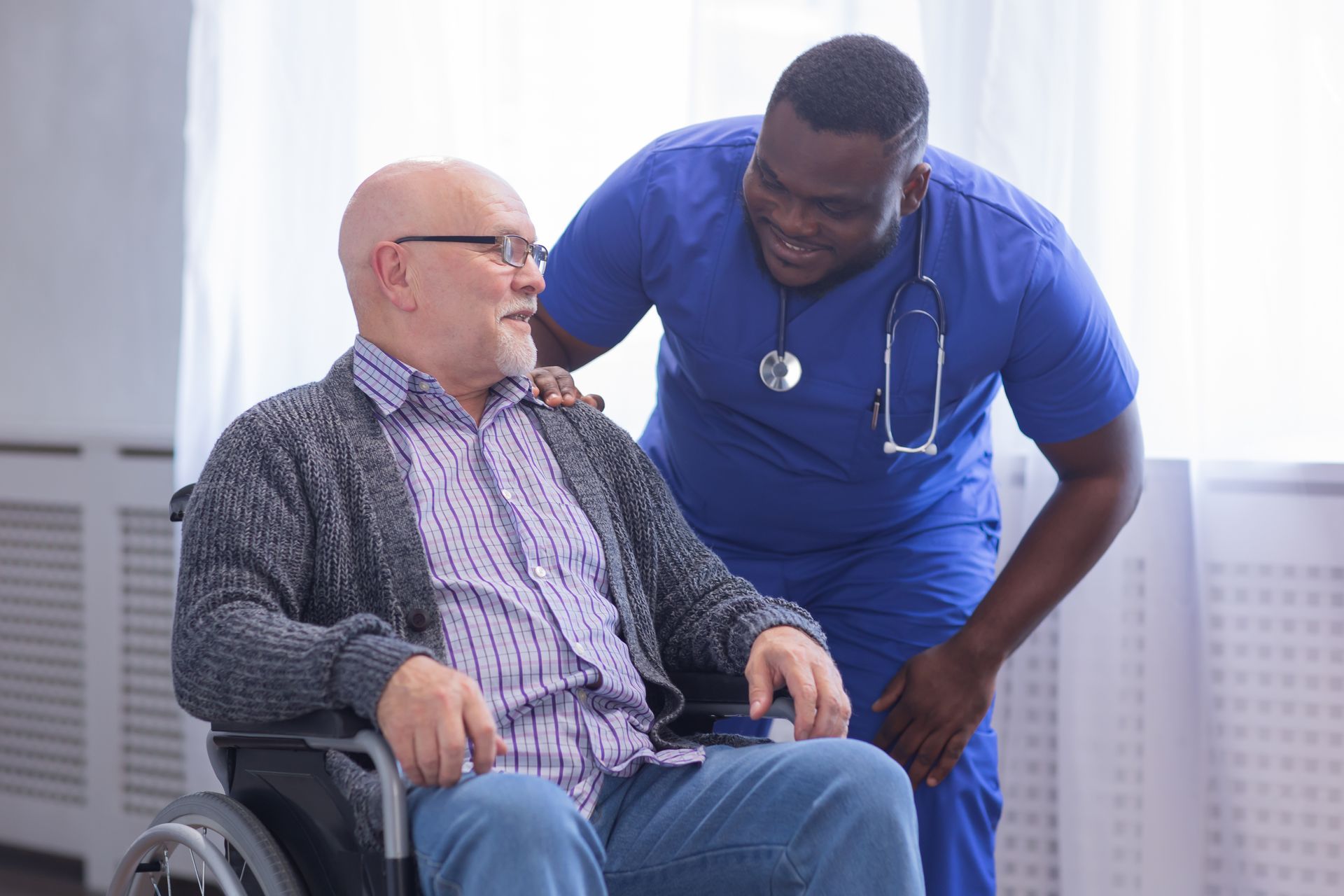A nurse is helping an elderly man in a wheelchair.