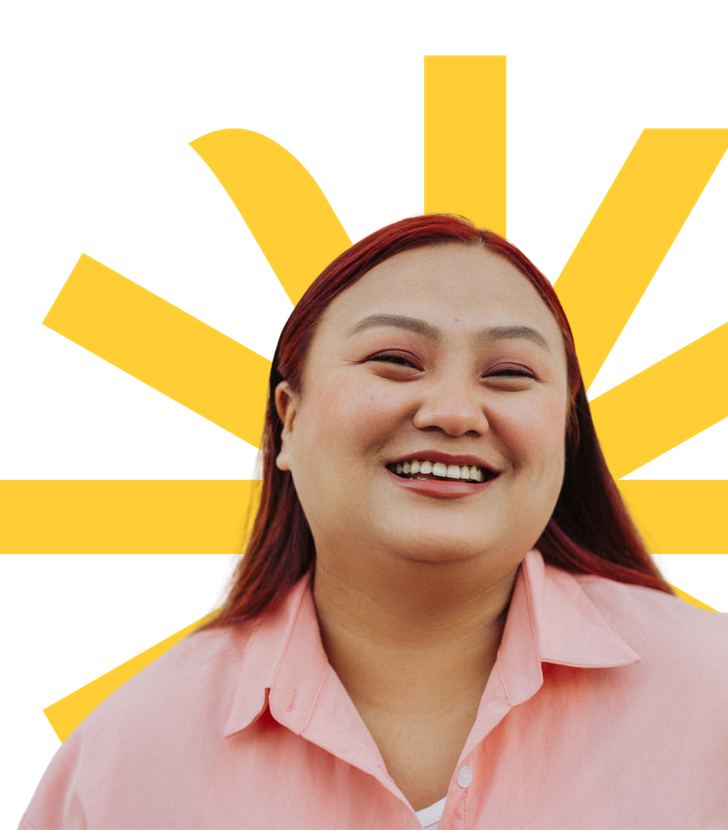 Smiling person in a pink shirt with yellow rays behind them on a white background