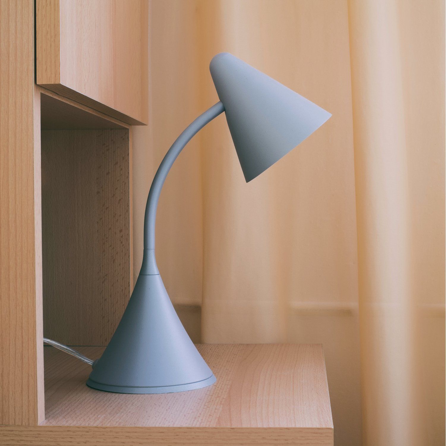A white lamp with a cone shaped shade on a white background