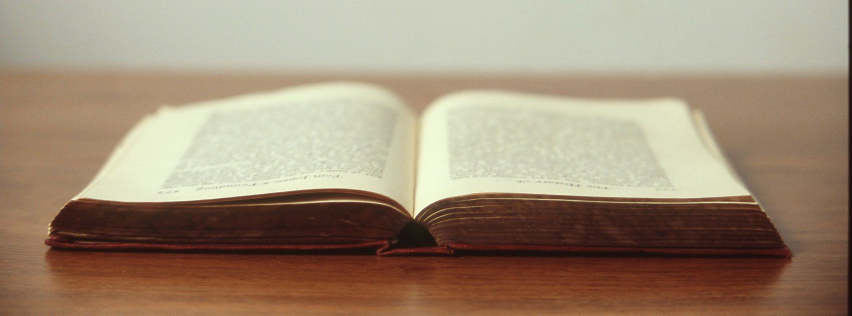 An open bible is sitting on a wooden table.