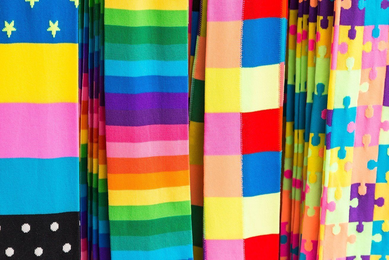 A bunch of colorful socks are hanging on a rack.
