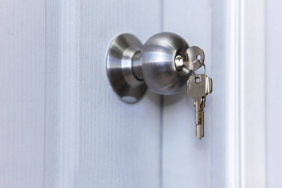 A close up of a door knob with two keys in it.