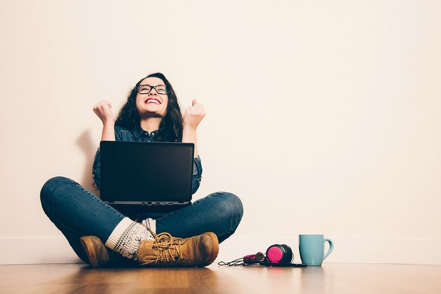 A woman is sitting on the floor using a laptop computer.