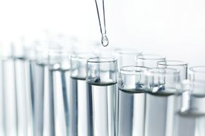 Droplet dispensing into glass test tubes in a bright laboratory setting
