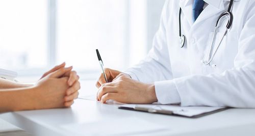 A doctor is sitting at a table talking to a patient.