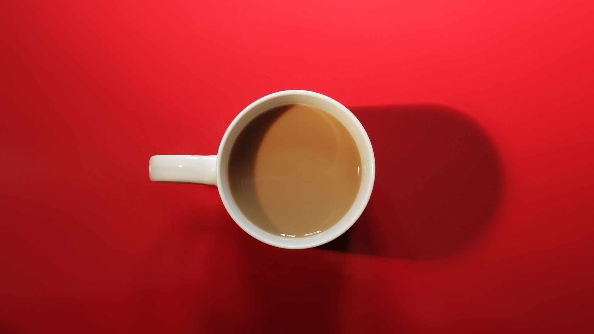 A cup of coffee is sitting on a red table.