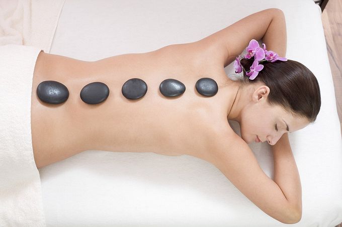 Eine Frau liegt auf einem Bett und bekommt eine Hot-Stone-Massage.