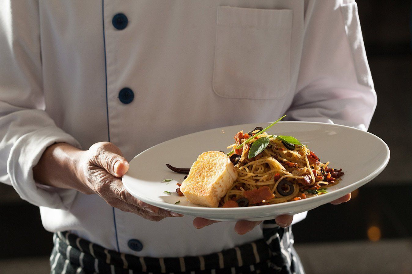 A chef is holding a plate of food in his hands.