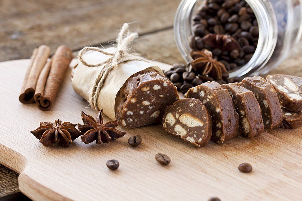 Chocolate salami dessert on a wooden board, with coffee beans, star anise, and cinnamon sticks.