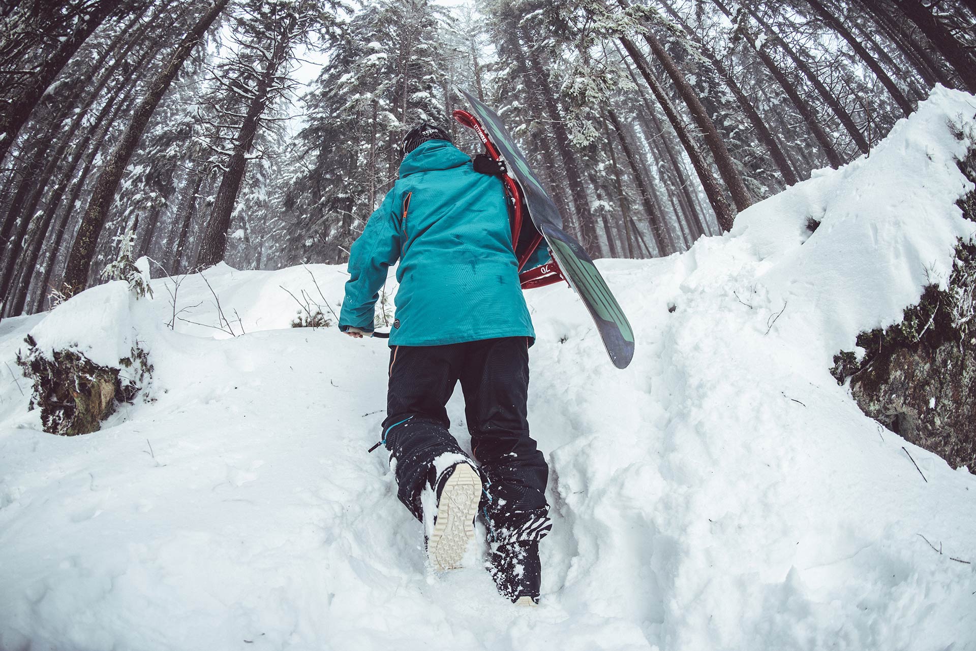 A person is carrying skis on their back while walking through the snow.