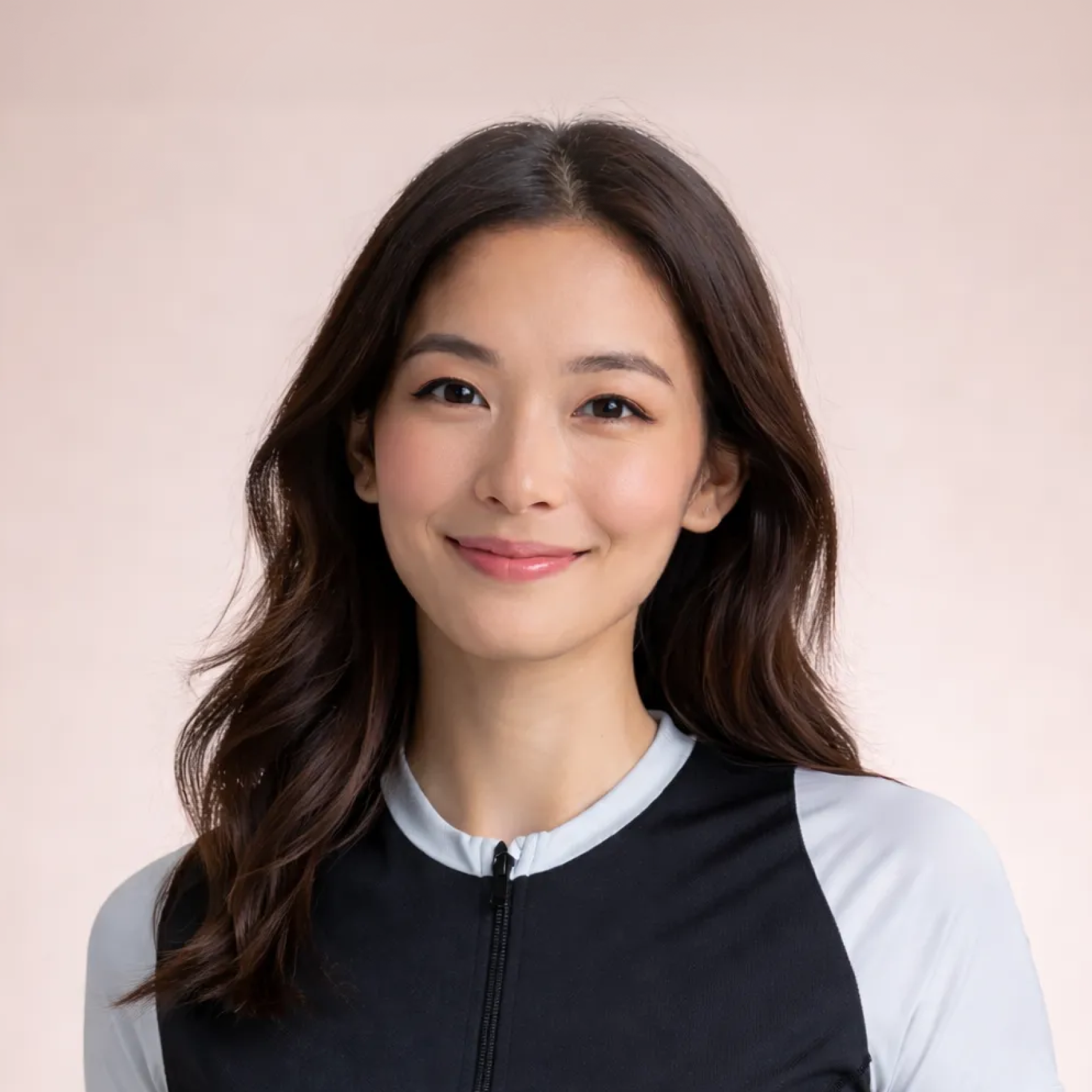 Portrait of a smiling person with long dark hair in a black-and-white top against a soft beige background