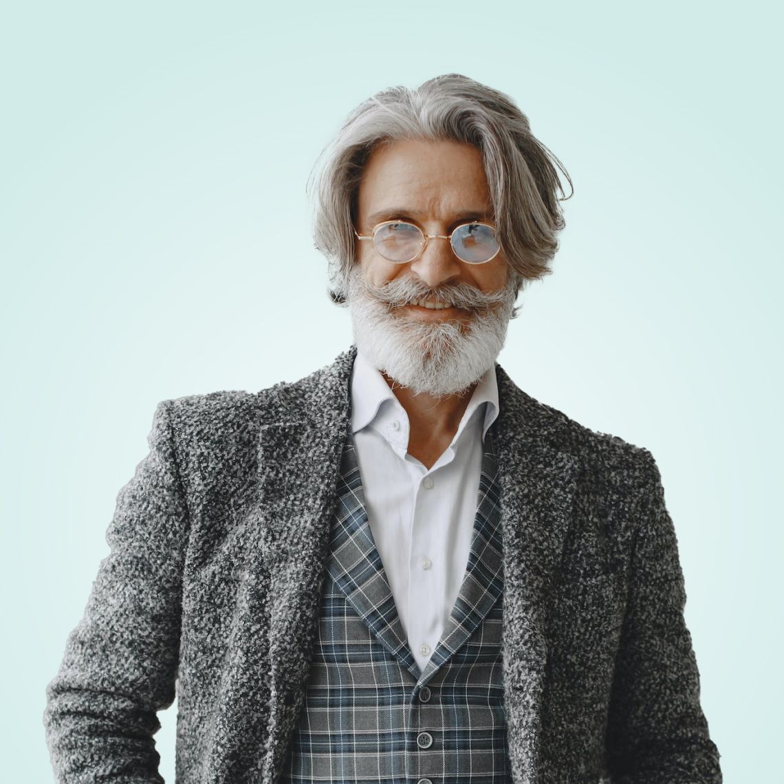 Portrait of a smiling man in glasses and a gray textured suit against a light blue background