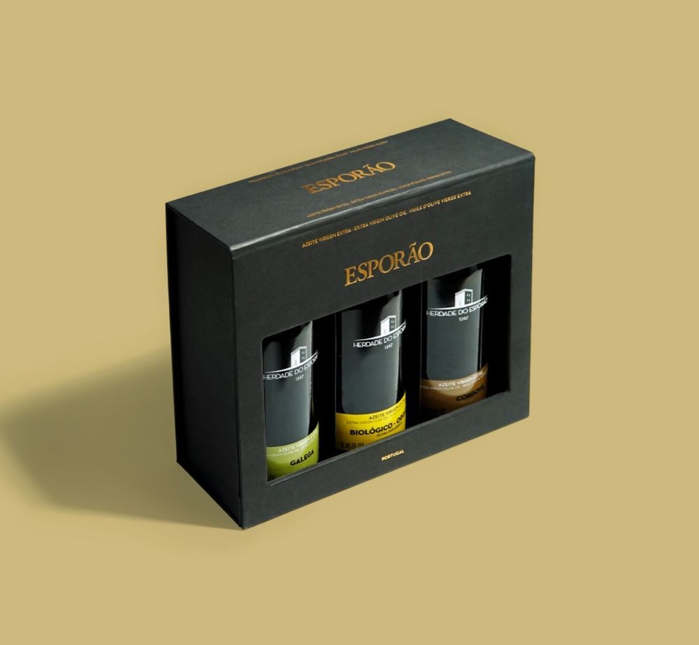 Black box set with three glass bottles of Esporão products, against a yellow-brown background.