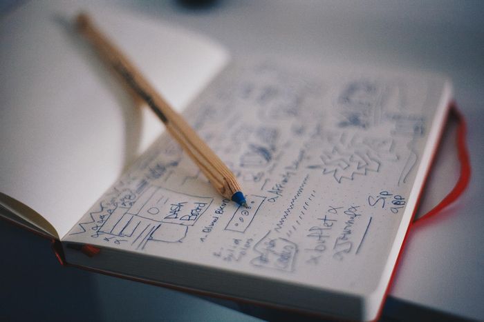 A pencil is sitting on top of a notebook with drawings on it.