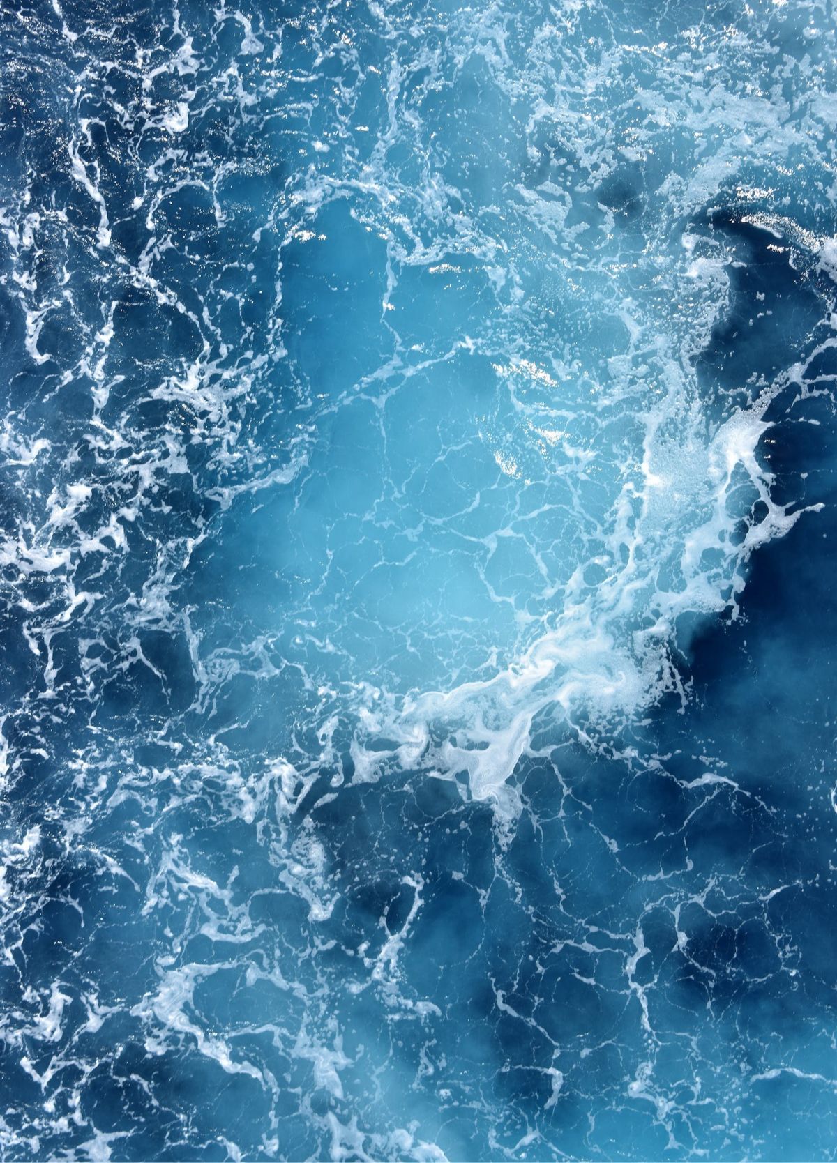 Churning blue ocean water with white foam.