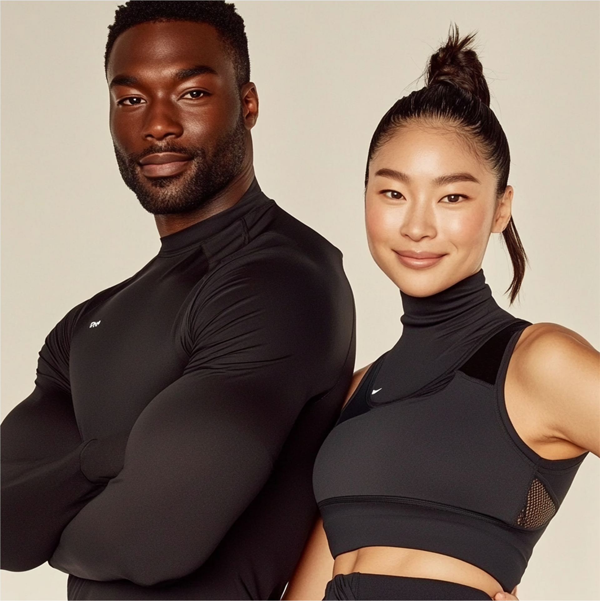Man en vrouw in zwarte sportkleding, lachend, poserend samen. Crèmekleurige achtergrond.